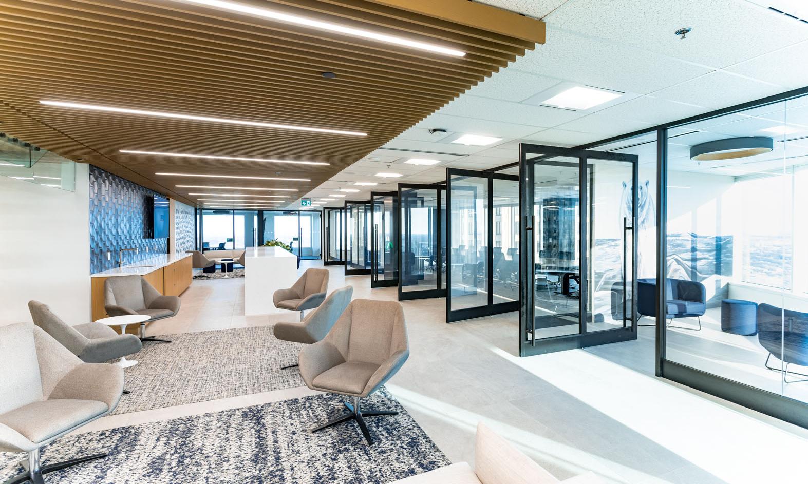 BDO Winnipeg. The new, lower-level client lounge showing the staircase to the upper floor and comfortable seating in the foreground.