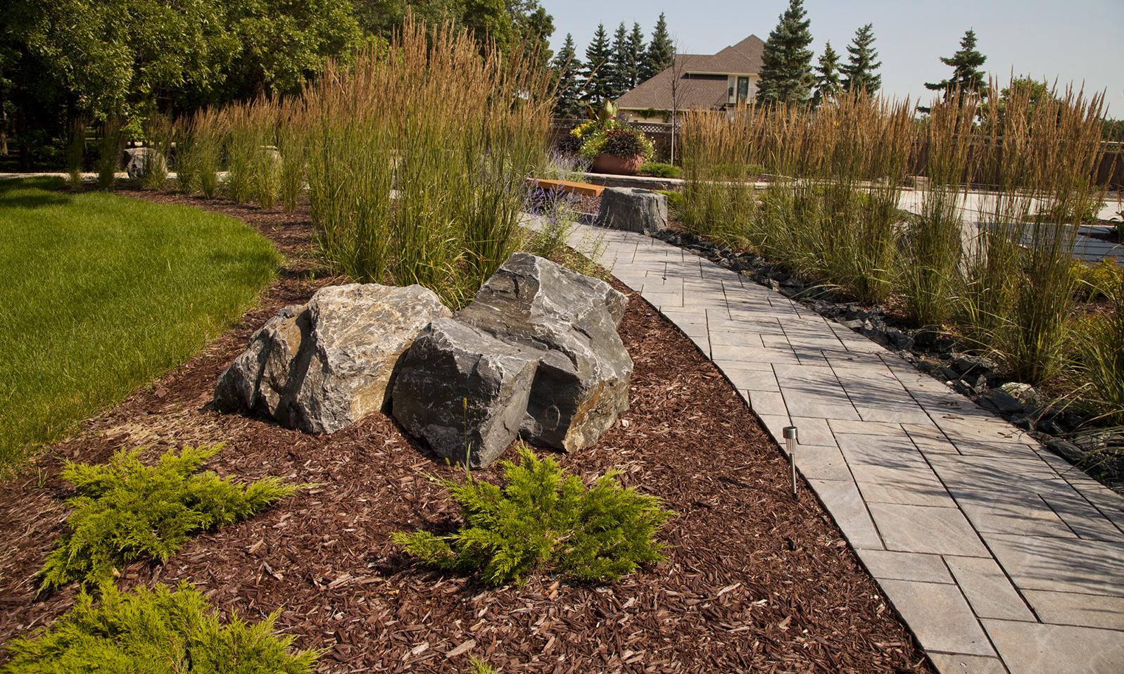 Private Residence. Pathway as seen from closer up focusing on an arrangement of large boulders in the foreground.