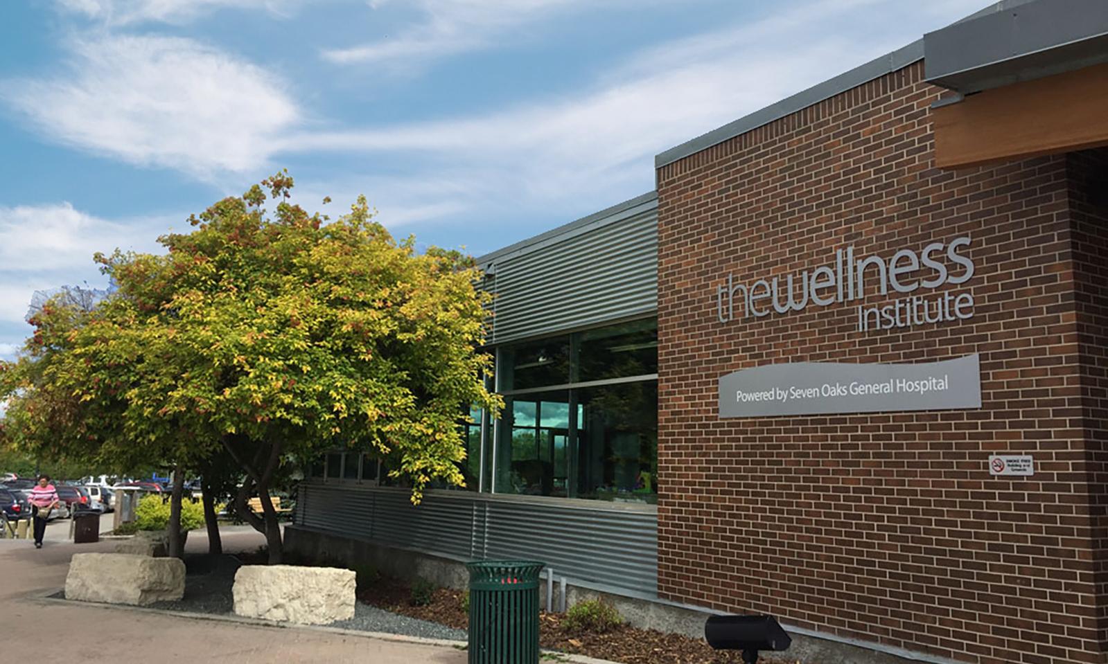 Seven Oaks General Hospital Wellness Institute. The Wellness Institute entrance with pea gravel walkway, large limestone blocks under an arced line of trees.